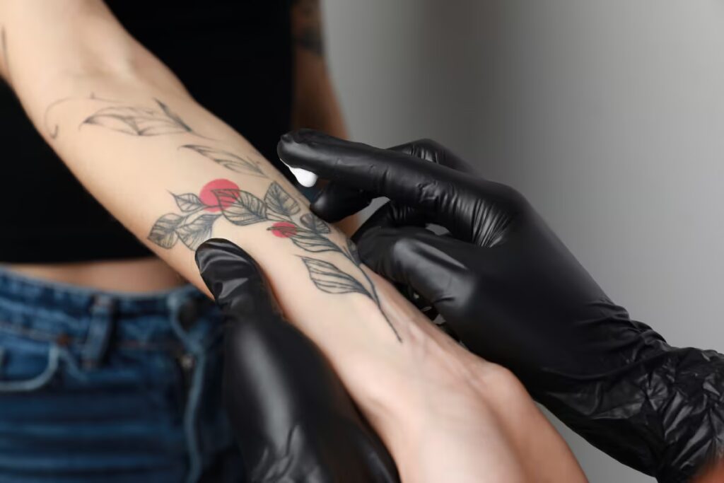 tatuador-experiente-passando-creme-hidratante-na-tatuagem-da-cliente-no-antebraço