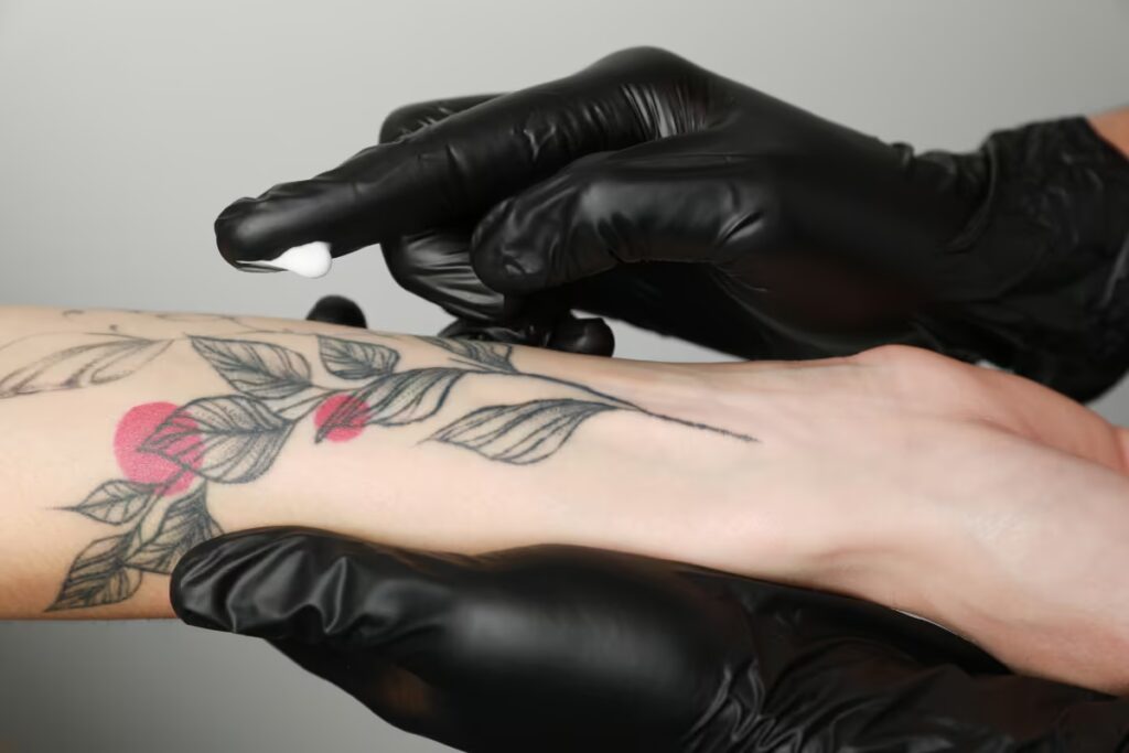 tatuador-experiente-passando-creme-hidratante-na-tatuagem-da-cliente-no-antebraço-direito